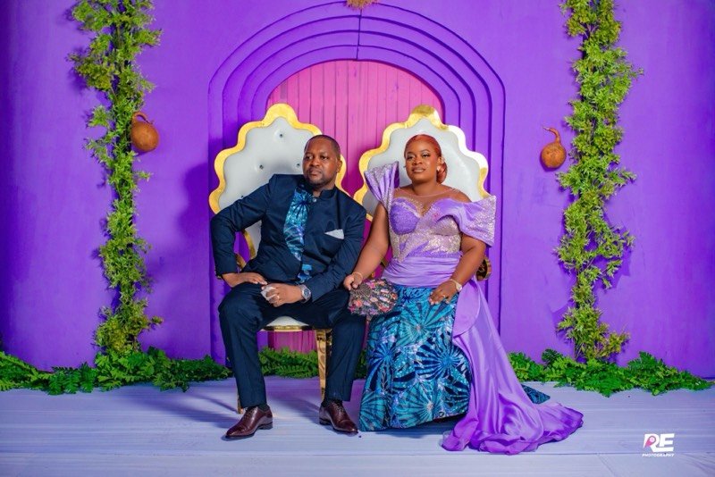 Un couple assis sur deux trônes dans un décor violet