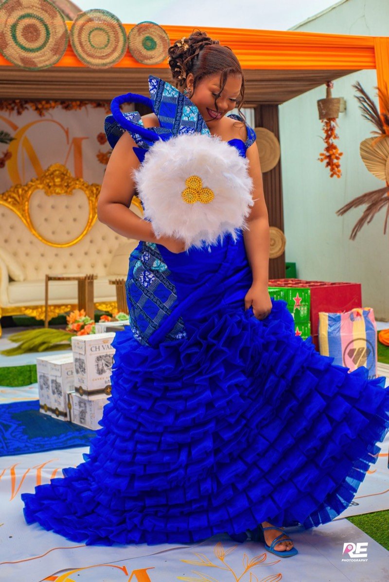 Femme en robe bleue à volants, éventail de plumes à la main