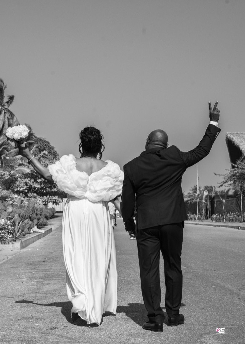 Les mariés s’éloignent, bouquet levé, en noir et blanc