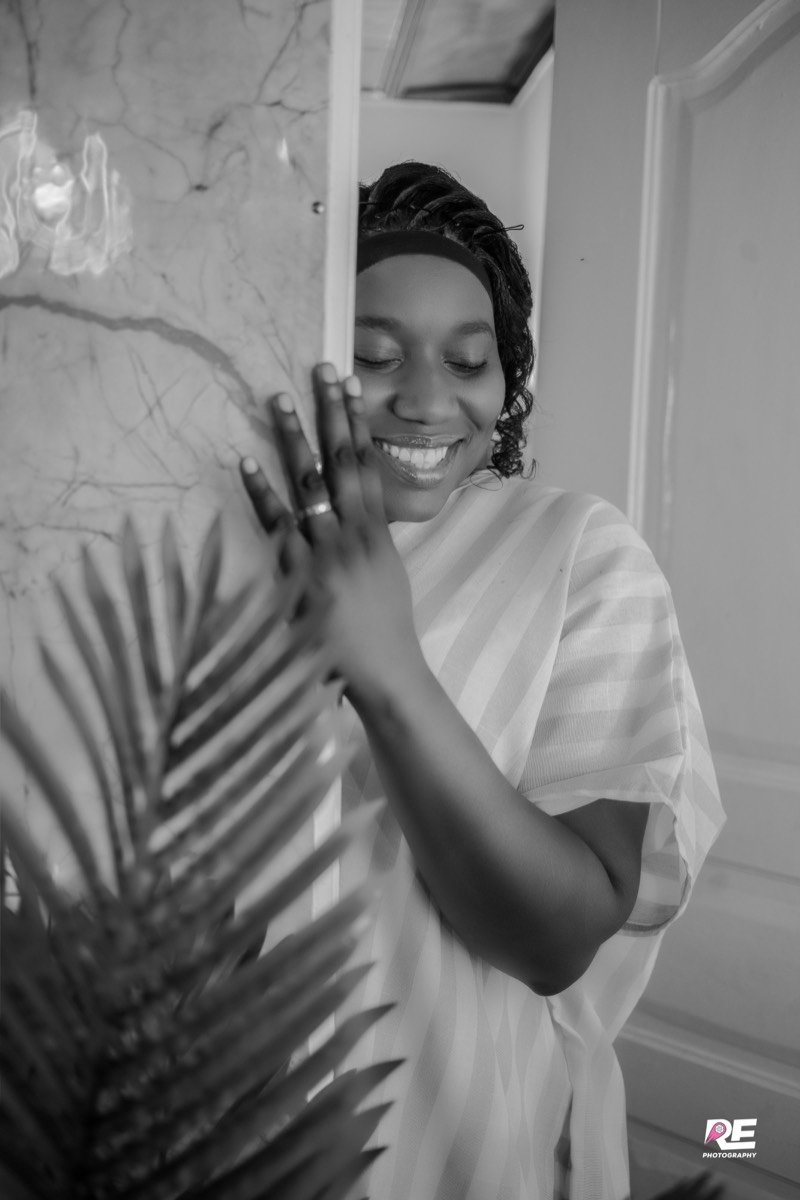 Femme souriante, les yeux fermés, appuyée contre une colonne, en noir et blanc